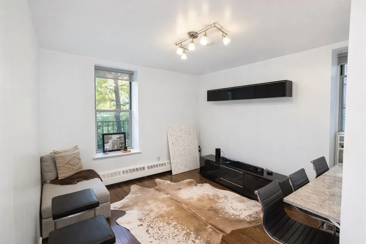Bright modern living room with a cowhide rug, black media console and daylight through a large window after real estate photo enhancement