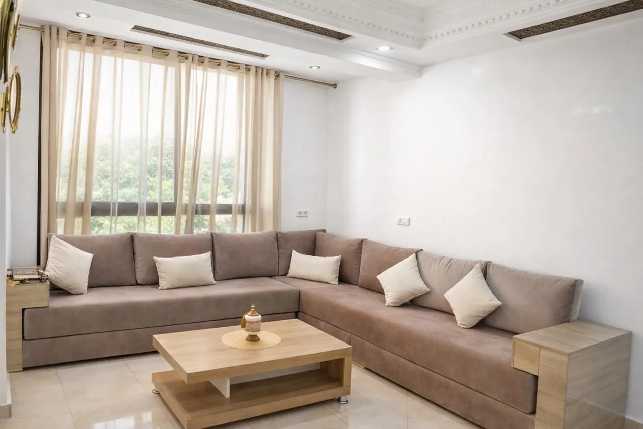 Bright traditional Moroccan-style living room with a taupe sectional, sheer curtains and ornate ceiling molding after photo enhancement