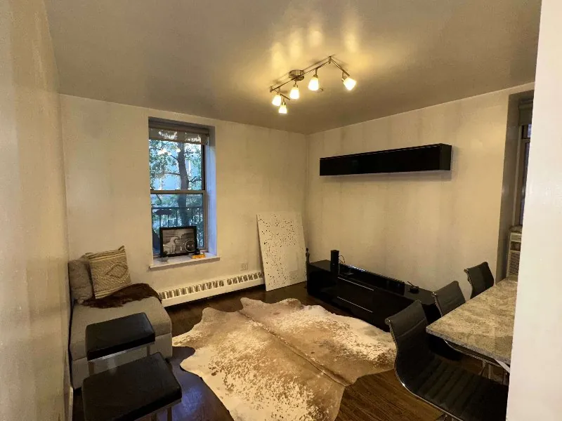 Bright modern living room with a cowhide rug, black media console and daylight through a large window after real estate photo enhancement (original, before AI enhancement)